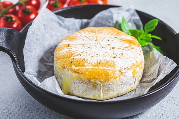 Camembert al forno o formaggio brie in una padella nera.