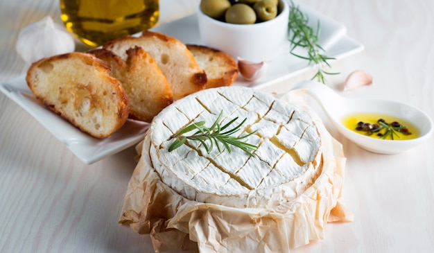 Baked camembert or Brie cheese on a wooden board.