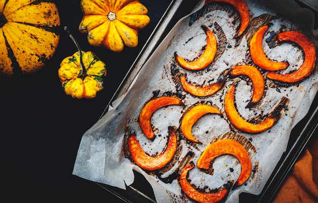 Baked caramelized pumpkin slices on parchment paper autumn food Rustic style Top view