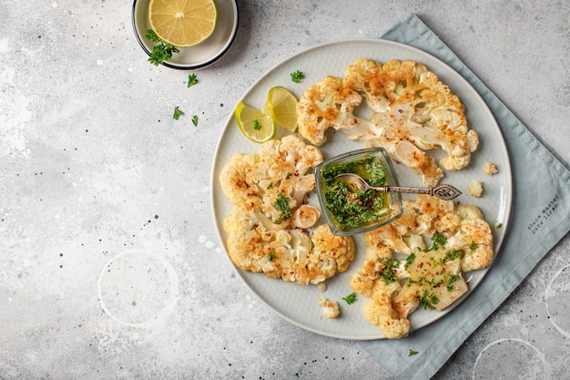 Baked cauliflower steaks with pesto. light . top view. copyspace