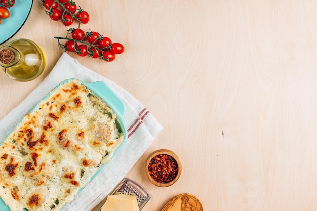 Baked cheesy meatballs casserole in the oven dish on wooden background