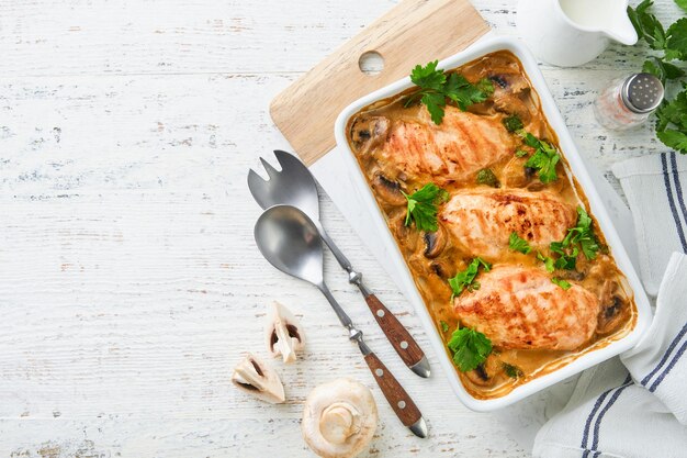 Baked chicken breast bbq with mushrooms and garlic in cream sauce on white wooden table backgrounds Top view image with ingredients for cooking Top view with copy space