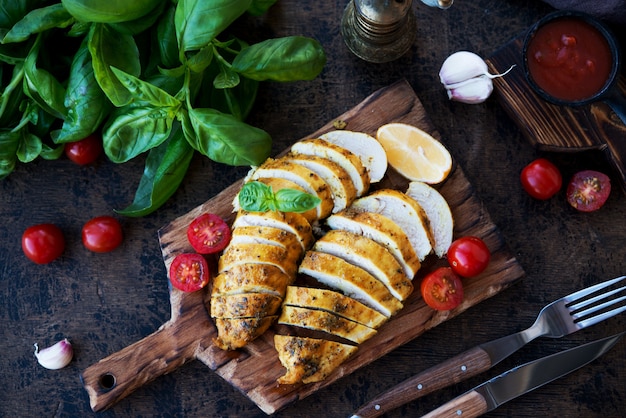 Baked chicken breasts on a wooden board with vegetables, selective focus, top view