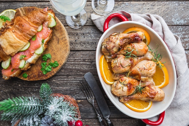 Baked chicken drumstick in a dish with orange and rosemary, top view