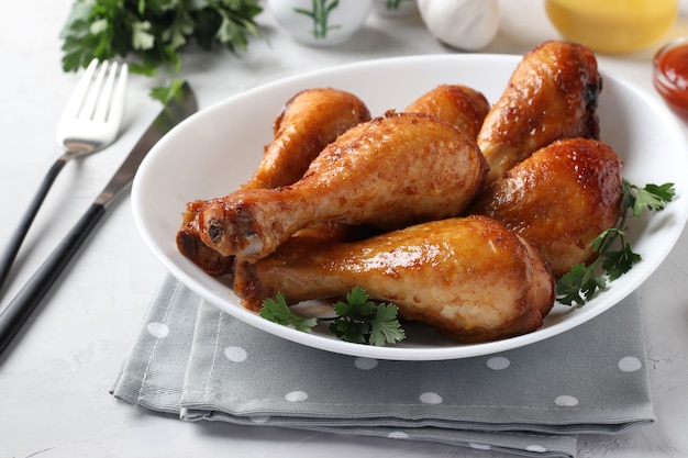 Baked chicken drumsticks in honey and soy sauce on white plate with parsley.