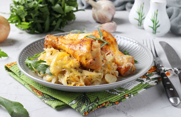 Baked chicken drumsticks with cabbage and garlic on gray plate