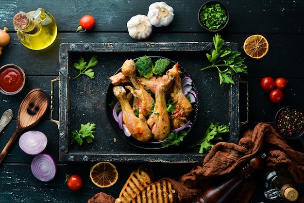 Baked chicken drumsticks with vegetables on a black plate Chicken meat Top view Free space for your text