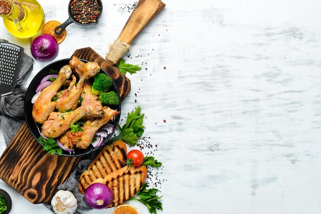 Baked chicken drumsticks with vegetables on a black plate Chicken meat Top view Free space for your text