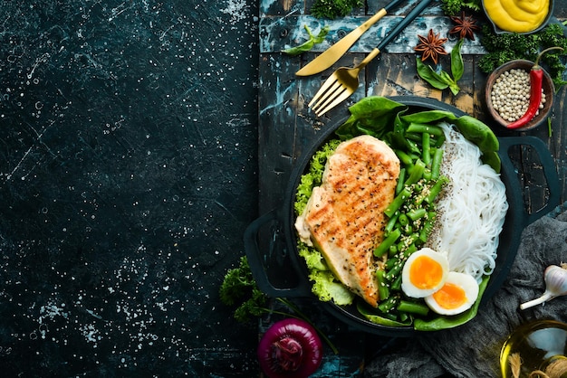 Baked chicken fillet with rice pasta spinach and beans in a black stone plate Dietary food Top view Free space for text