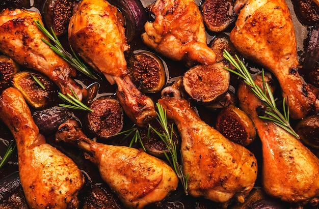 Baked chicken legs drumsticks with sweet figs and red onions in balsamic marinade on baking sheet close up top view