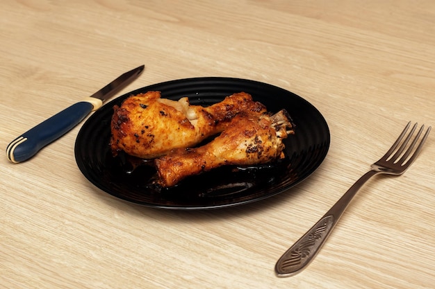 Baked chicken legs on a plate fork and knife