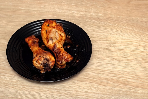 Baked chicken legs on a plate on wooden table