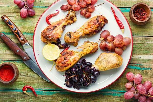 Baked chicken legs with grapes on rustic wooden table