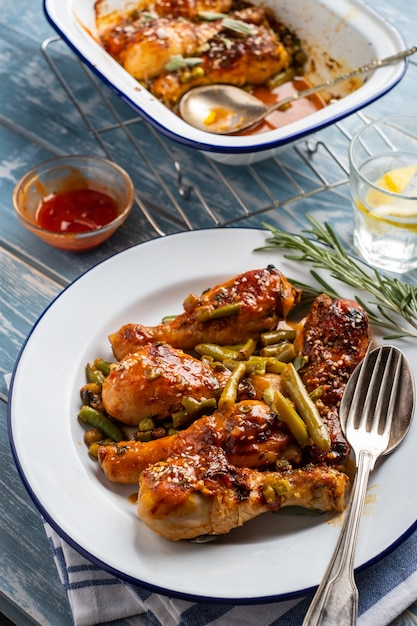 Baked chicken legs with peas, beans and fresh herbs. Chicken drumsticks with tasty sause and greens.