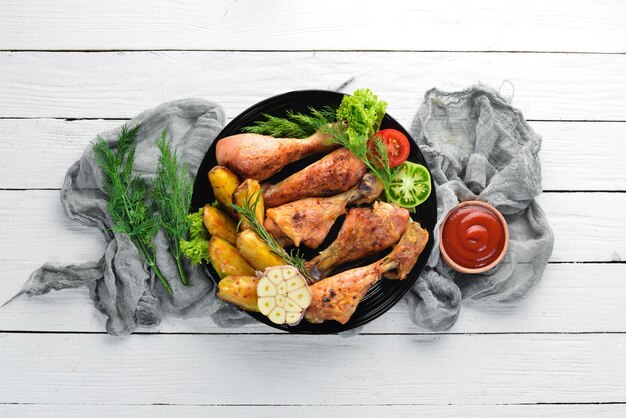 Cosce di pollo al forno con patate e verdure su fondo di legno bianco carne vista dall'alto spazio libero per la copia