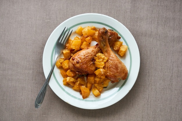 Baked chicken legs with pumpkin on a white plate