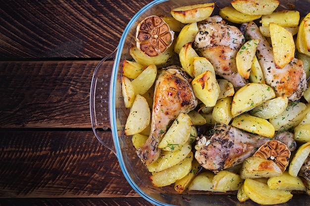 Baked chicken legs with sliced potatoes and herbs.