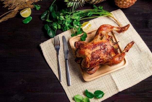 Pollo al forno posto su un piatto di legno in vista dall'alto.