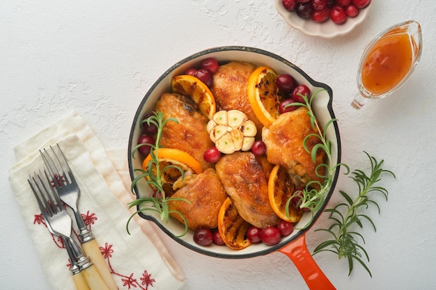 오렌지 크랜베리와 매운 허브 로즈마리를 곁들인 구운 닭 허벅지는 밝은 배경의 프라이팬에 제공됩니다 축제 크리스마스 저녁 개념 메뉴 상위 뷰 복사 공간