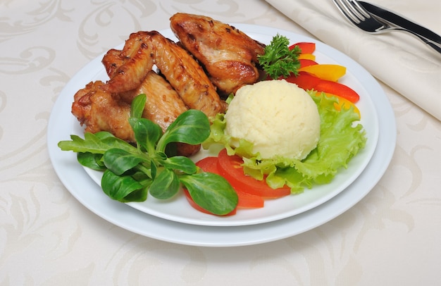 Photo baked chicken wings in honey and soy marinade with garlic and potatoes and vegetables