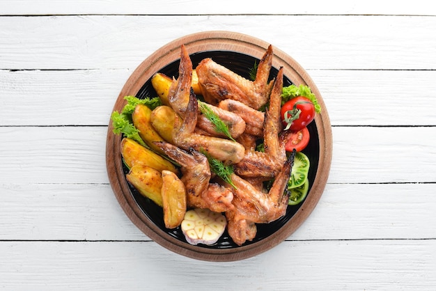 Baked chicken wings with potatoes and vegetables on a white background Meat Top view Free copy space