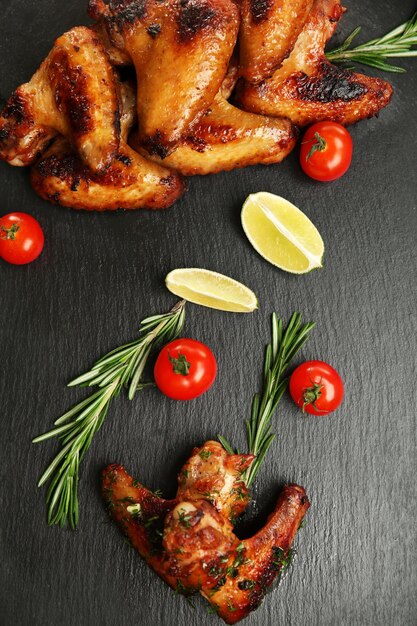 Baked chicken wings with tomatoes and rosemary on slate plate