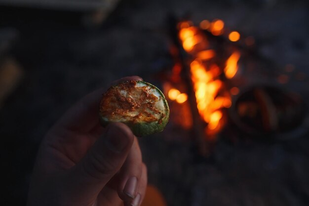 夜のピクニックでキャンプファイヤーを背景に焼きズッキーニ