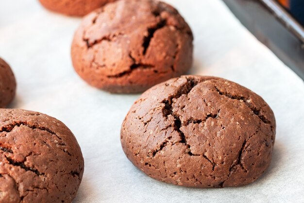 Baked cracked round chocolate cookies on a baking sheet