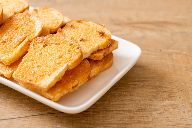 baked crispy bread with butter and sugar on plate