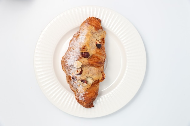 baked croissant with nuts on a white plate