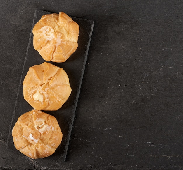 Eclairs di crema pasticcera al forno su un bordo nero