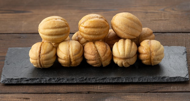 Baked dessert nuts with condensed milk on black slate board, top view