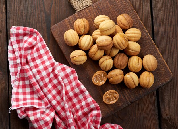 Baked dessert nuts with condensed milk on a wooden board, top view