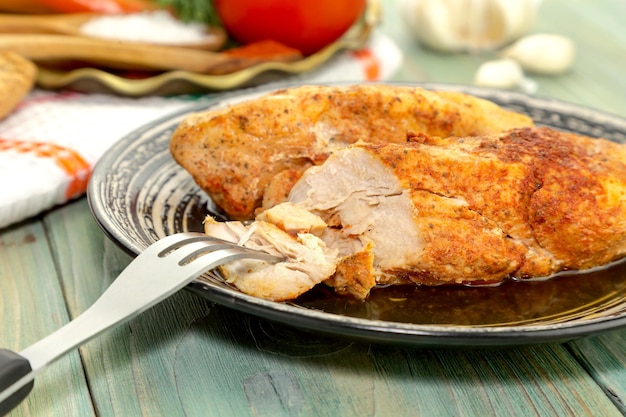 Baked dietary chicken breast with spices on a plate closeup on a wooden table