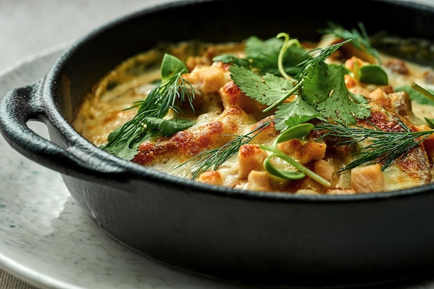 Baked draniki in cream sauce with bacon on a plate on a textured background. Close-up