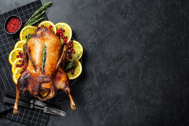 Baked duck stuffed with oranges and rosmarina. Festive table. Black background. Top view. Space for text