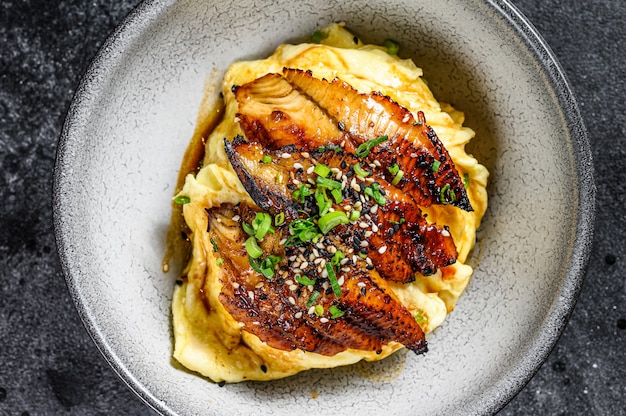 Baked eel with Japanese omelette and rice. Black background. Top view.