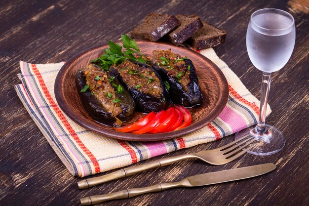 Запеченные баклажаны, фаршированные луком, алычой и грецкими орехами на тарелке крупным планом