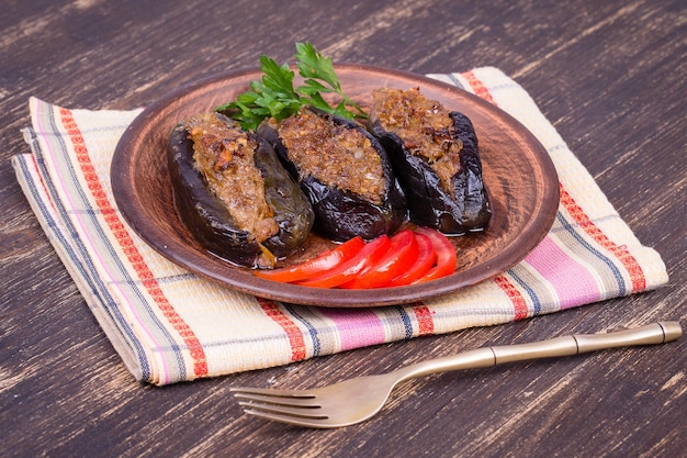 Baked eggplant stuffed with onions cherry plums and walnuts on the plate close up