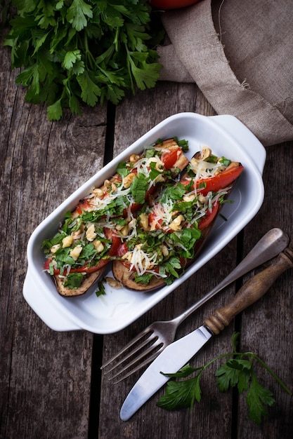 Baked eggplant with cheese, tomato, herbs and nut. Selective focus