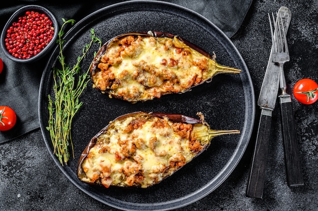 Baked eggplant with tomatoes and cheese. Black background. Top view.