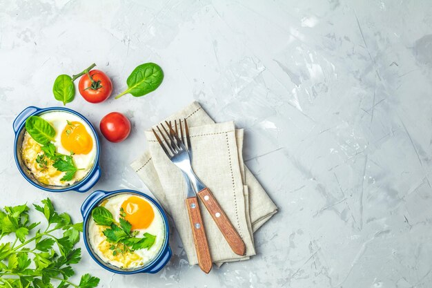 Baked eggs in blue ceramic baking molds Portioned casserole from vegetables and eggs in Italian or french style Eggs kokot cocotte breakfast Top view copy space for you text