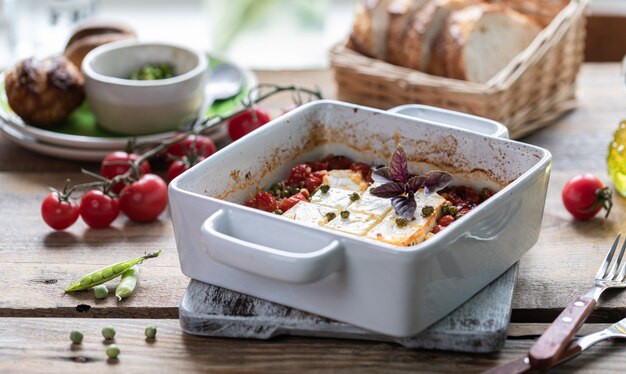 Baked feta cheese with cherry tomatoes with basil and olive oil. Greek national cuisine.