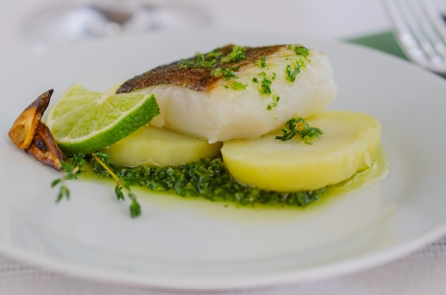 Baked fillet fish with garnish and sauce in the restaurant table .