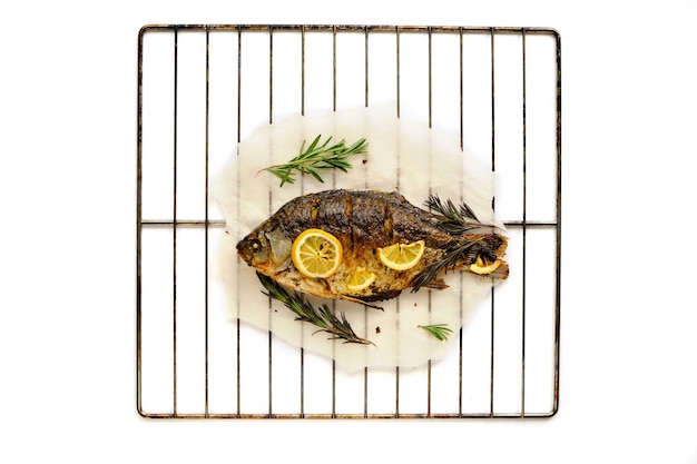 Baked fish cooked on parchment paper with spices lemon and rosemary barbecue grill with white background