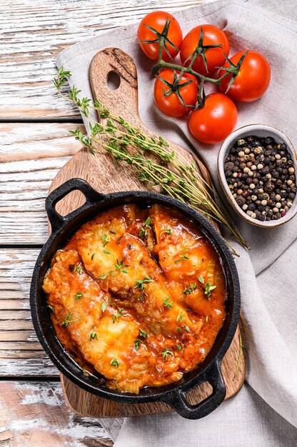 Baked fish in a pan with tomato sauce