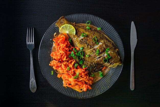 Baked fish in a plate isolated on black background