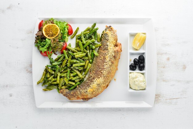 Baked fish Trout baked with green beans On a wooden background Top view Free copy space