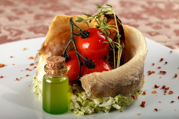 Baked fish on a vegetable side dish with cherry tomatoes.