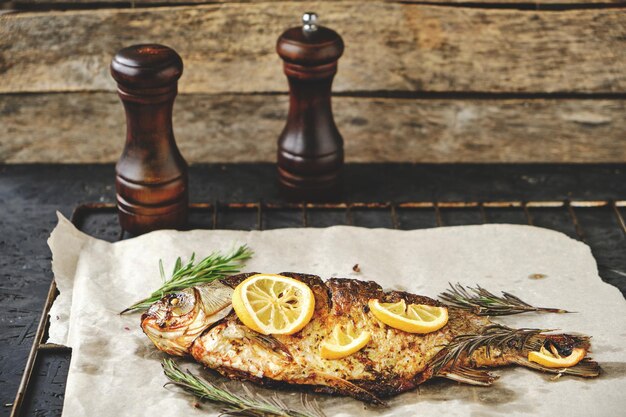 Foto il pesce al forno con erbe e limone è disposto su carta pergamena con cannucce sullo sfondo